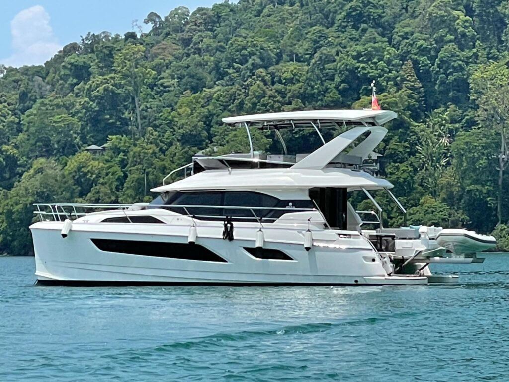 Aquila 44 Yacht 2020 cruising on serene waters with lush green forest backdrop.