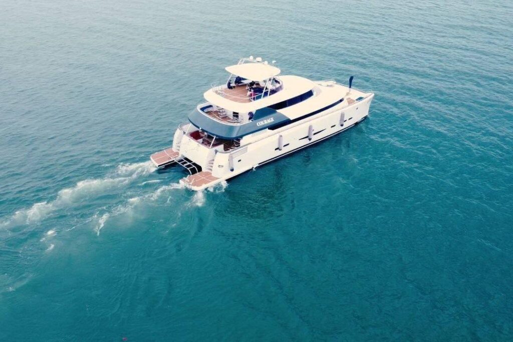 Aerial view of a custom luxury yacht cruising in clear blue ocean waters