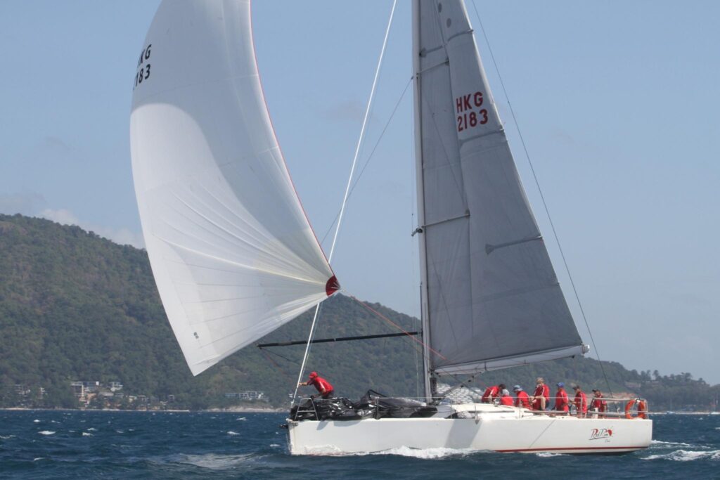 2010 Archambault A40 RC sailboat racing on open water with crew in red attire.