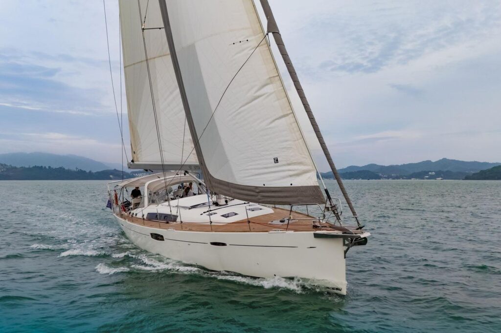 Sailing yacht on the water with mountains in the background.