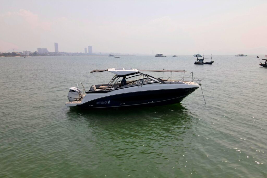 MAKO I boat anchored in calm water, with city skyline in the distance.