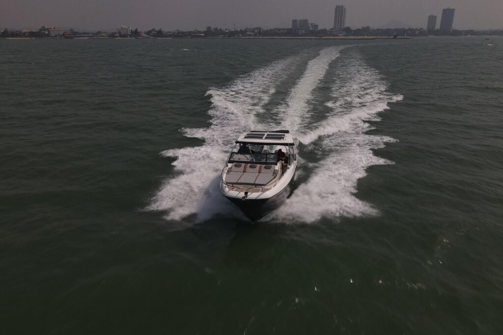 Boat speeding across the water, leaving a white wake towards the city skyline.