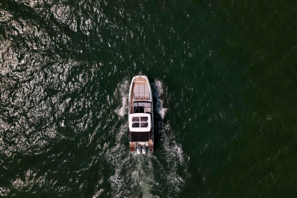 Boat cruising on the water, leaving a white wake behind. Aerial view.