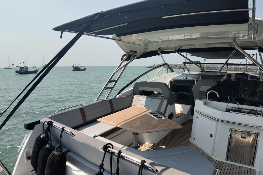 Boat interior with seating, table, and ocean view featuring other boats in the distance.