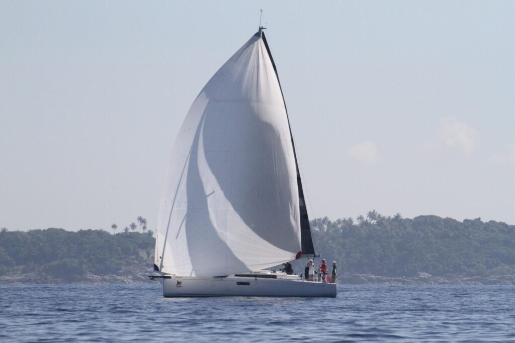 2023 Beneteau First 36 sailboat gliding on calm waters near a lush coastline.