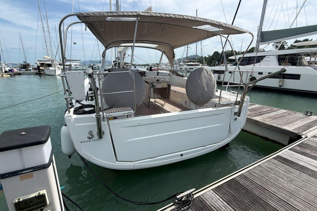 White Beneteau sailboat docked at a marina, stern view.