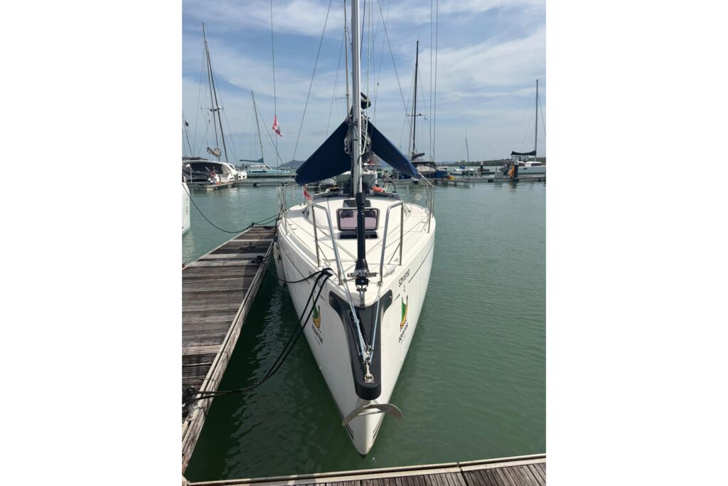 White sailboat, Duan Duan, docked at a marina with a blue sail cover.