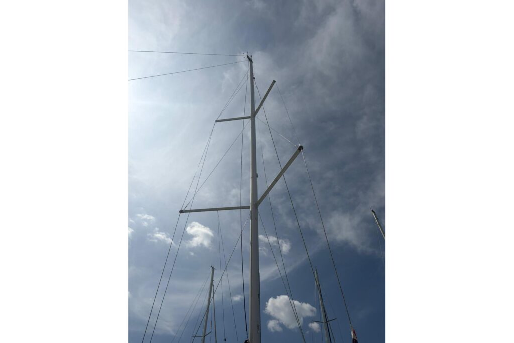 Sailboat masts reaching into a blue sky with scattered clouds.