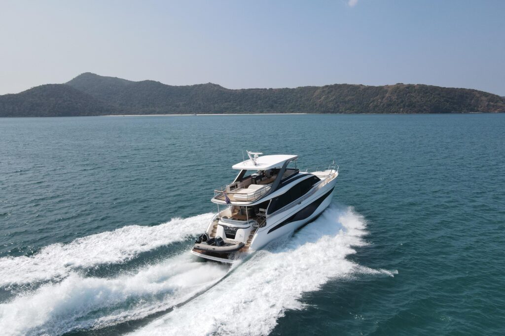 Luxury yacht cruising on blue water with island in background. La Mer.