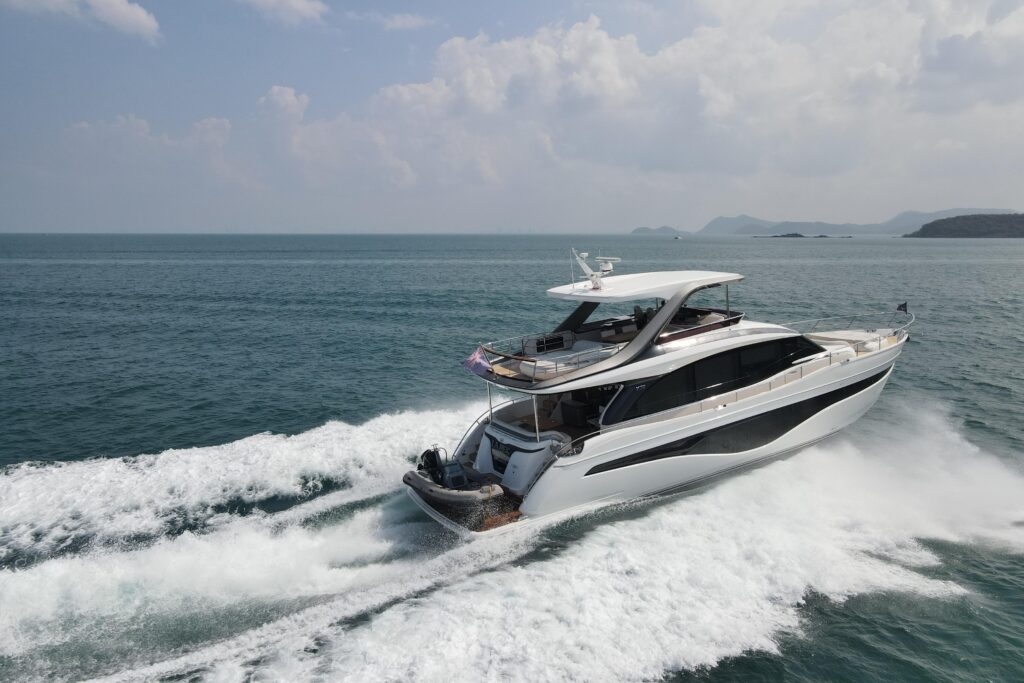 Luxury yacht cruising on the water with a dinghy on the back.