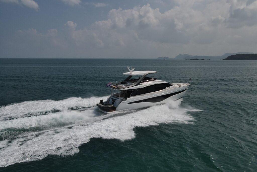 Luxury yacht speeding across the blue sea, creating white water wake.