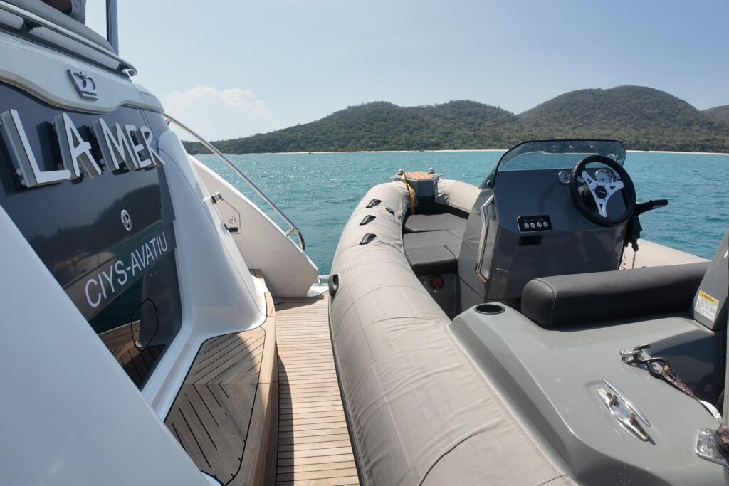 La Mer yacht tender boat docked, turquoise water and island view.