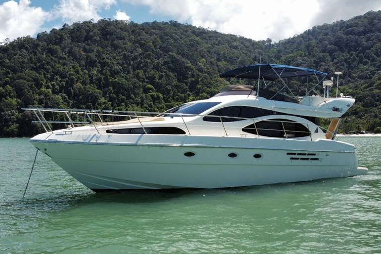2002 Azimut 46 yacht on serene water with lush green hills in the background.