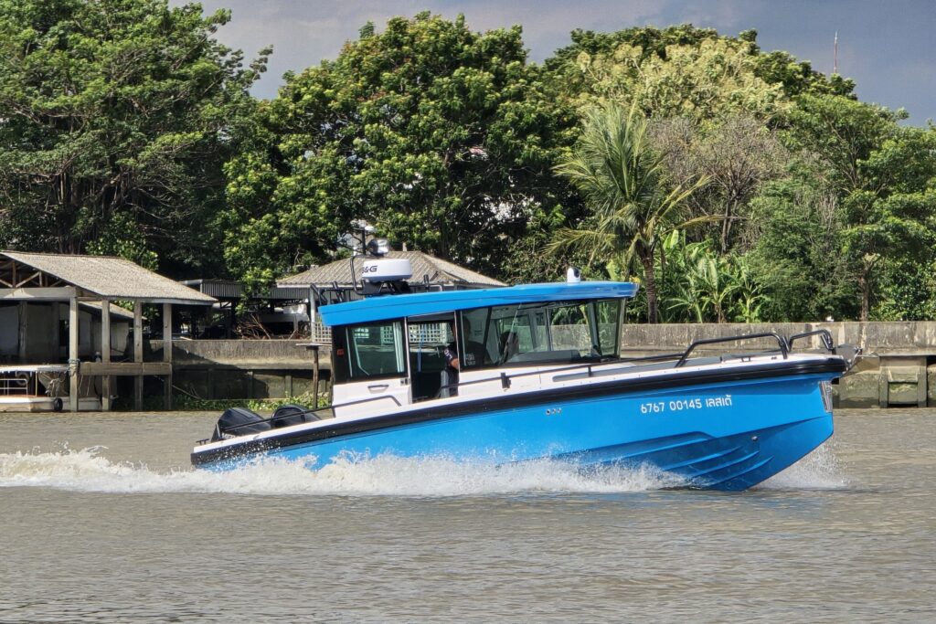2023 Axopar 28 Cabin boat cruising on a river with lush greenery background.